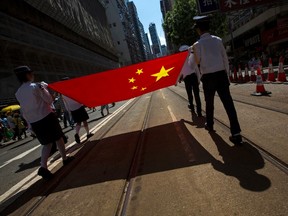 Youth uniformed group members carry a Chinese national flag during a march in the streets to demonstrate against a pro-democracy Occupy Central campaign in Hong Kong, in this August 17, 2014 file picture. China and Hong Kong have been wrangling over what it means to have "one country, two systems" for the past 30 years - China stressing "one country" and democrats in the former British colony the "two systems". For Beijing, Western-style democracy conjures up visions of "colour revolutions" and the "Arab Spring", of chaos and instability that could pose a mortal threat to the ruling Communist Party. For many Hong Kong residents, free elections means preserving the British-instituted rule of law, accountability of leaders, and multi-party politics as a check on government powers. To match Insight CHINA-HONGKONG/      REUTERS/Tyrone Siu