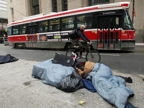 A homeless person is seen lying on the street in downtown Toronto in this undated file photo. (QMI Agency files)
