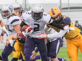 A Western Mustangs ball carrier battles the elements and Queen's Golden Gaels defenders on a rainy and cold day during OUA action at Richardson Stadium on Saturday. (Julia McKay/The Whig-Standard)