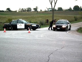 OPP officers converse at a roadblock set up at Hwy. 4 and Conservation Rd. north of Clinton Sunday morning. Police have sealed off an area around the Hullett Conservation area. John Miner/ The London Free Press