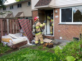 Firefighters talk at the back door of a townhouse at 1159 Huron St. following a morning fire at the London-Middlesex Housing Corp. complex in London on Sunday 
CRAIG GLOVER/The London Free Press/QMI Agency