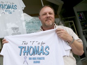 Emily Mountney-Lessard/The Intelligencer
Steve Hannah of downtown business Reiki on Wheels, which shares a storefront with Ray and Jim's Signs and Trophies, is shown here Monday with T-shirts that are for sale to benefit Thomas Martin and his family.
