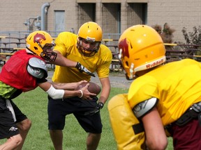 Quarterback Quinton Auty, left, hands the ball to Justin Saba as Damon Matos gets ready to block him as the Regiopolis-Notre Dame Panthers senior football team prepares Monday for the Kingston Area Secondary Schools Athletic Association 2014 season. (IAN MACALPINE/THE WHIG-STANDARD)