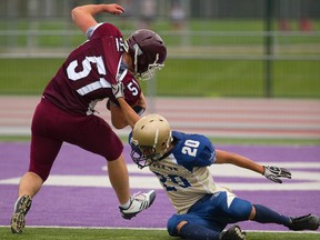 Matt Day of John Paul II is grabbed by the collar by Regina Mundi?s Zuffi Abbas, but still makes it into the end zone during the first half of their TVRA United Way game at TD Stadium on Monday. A horse-collar penalty was applied to the following kickoff.  (Mike Hensen/The London Free Press)