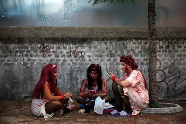 Players dressed as zombies chat and check their phones as they wait for the start of the "Survival Zombie" competition in Collado Villalba, outside Madrid, September 6, 2014. According to the back-story of the "Survival Zombie" contest, participants, who signed up as survivors, are trapped for a night in a city that has been infected with a virus that causes humans to turn into zombies. The objective of the game is for the survivors to stay alive until morning by avoiding getting touched by a zombie. In order to do so, the contestants need to find clues that will help them reach a safe haven, the end point of the contest. Survivors are not allowed to attack the zombies, a role made up of other players as well as members of the contest organization, so their only means of survival is by avoiding them. A single touch of a zombie eliminates the player, but they can return as zombies after getting made up, so that they can continue playing. A group of actors dressed as soldiers are also involved in the game, helping some players against the zombies or making it harder for others to solve the clues to survive.  Picture taken September 6, 2014. REUTERS/Susana Vera