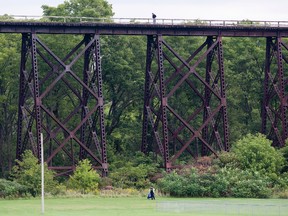 A police officer guards the scene on the ground while another takes photographs from atop a railway trestle bridge in St. Thomas, Ontario on Monday, September 15, 2014. (DEREK RUTTAN, The London Free Press)