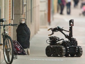 A police bomb disposal robot moves in on the smaller of two suspicious packages located in front of the Central Library's Dundas Street entrance in London, Ont. on Monday September 15, 2014. (MIKE HENSEN, The London Free Press)