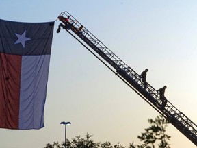 Firemen descend after hanging a Texas flag from ladder trucks.
REUTERS/Richard Carson