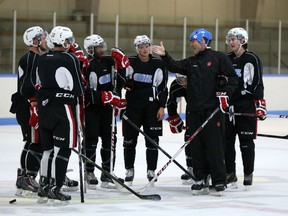 Ottawa 67's head coach Jeff Brown, wearing the bucket helmet from his days with the Quebec Nordiques, speaks to some of the players during practice at the Fred Barrett Arena Tuesday. (Chris Hofley/Ottawa Sun)
