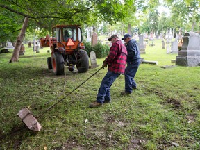 A Woodland Cemetery crew recovers a stone spire from a ravine at the edge of the Springbank Dr. property in London Tuesday. The cemetery had been dumping old tombstones in the ravine. (CRAIG GLOVER / The London Free Press)