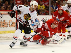 Niklas Hjalmarsson of the Chicago Blackhawks tries to get the puck past the diving Justin Abdelkader of the Detroit Red Wings during Game 4 of the Western Conference Semifinals at Joe Louis Arena on May 23, 2013. (Gregory Shamus/Getty Images/AFP)
