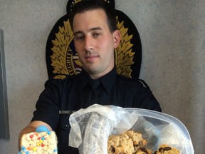 Const. Bryce Ottenbreit holds some baked goods made with drugs seized in a $300,000 drug bust. Ian Kucerak/Edmonton Sun