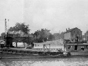The Hadley sand barge, circa 1910. North river bank near Fifth Street bridge. Old Klondike Hotel in background.
