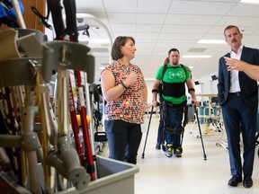 Col. Chris Hadfield, middle, talks with hospital staff as paraplegic Mike Munro walks with the aid of The Ekso Bionic Suit in a rehabilitation gym at St. Joseph's Parkwood Hospital in London, Ontario on Thursday September 18, 2014.  Munro, who was paralyzed from the waist down in a farming accident five years ago, is learning how to walk again through the aid of the exoskeleton suit which in part helps his legs relearn how to balance his weight.
CRAIG GLOVER/The London Free Press/QMI Agency