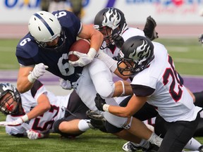 CCH running back Micah Sullivan bulls his way for extra yards before being tackled by Andrew Zooki and Luc Tourigny of Aquinas during their United Way football game at TD stadium on Thursday. CCH won 34-27. (Mike Hensen/The London Free Press)