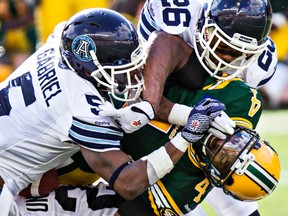Edmonton's Adarius Bowman (4) is tackled hard by Toronto's Jermaine Gabriel (5) and Branden Smith (26) during a game earlier this year. (Codie McLachlan, QMI Agency)