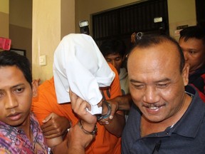 American Tommy Schaefer is escorted by police inside a police hospital to undergo medical checks in Denpasar on the Indonesian resort island of Bali  August 15, 2014. (REUTERS/Zul Edoardo)