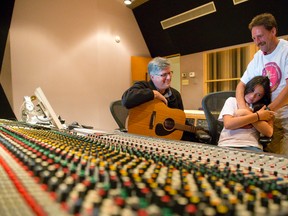 Songwriter, teacher and producer Steve Revington, left, shows Faith Abbey and her father, Dave, the soundboard used to record a collaborative song about Faith?s arsenal used to beat liver cancer at the age of two, at EMAC Studios in London.  Faith and her father completed a 96-km walk from London to Sarnia last week to raise money and awareness for Childcan, which supports children with cancer and their families. (CRAIG GLOVER, The London Free Press)