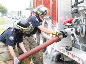 Belleville, Ont. firefighter Craig Letford, first from left, and his colleague from Station 3, Andrew McFarland remove a gushing hose from a tanker during a re-certification exercise held in Belleville's east end Saturday, Sept. 20, 2014. - Jason Miller/The Intelligencer