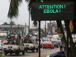 A U.N. convoy of soldiers passes a screen displaying a message on Ebola on a street in Abidjan August 14, 2014. The world's worst outbreak of Ebola has claimed the lives of 1,069 people and there are 1,975 probable and suspected cases, the vast majority in Guinea, Liberia and Sierra Leone, according to new figures from the World Health Organisation (WHO). Ivory Coast has recorded no cases of Ebola. REUTERS/Luc Gnago