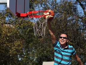 City councillor Michael Walters does his best Michael Jordan slam dunk impression -- with the help of a strategically placed garbage can -- at the ribbon cutting ceremony for the new Parkallen community league basketball court on Saturday, September 20, 2014 on Community League Day. CLAIRE THEOBALD Edmonton Sun