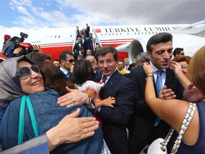 Turkish Consul General of Mosul Ozturk Yilmaz (2nd R) is welcomed by his relatives as Turkish Prime Minister Ahmet Davutoglu (C) looks on, as they arrive at Esenboga airport in Ankara September 20, 2014, in this handout courtesy of the Prime Minister's Press Office. Turkish intelligence agents brought 46 hostages seized by Islamic State militants in northern Iraq back to Turkey on Saturday after more than three months in captivity. REUTERS/Hakan Goktepe/Prime Minister Press Office/Handout via Reuters