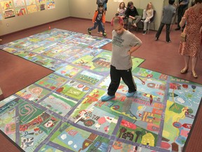 Niko Killam, a student from Frontenac Public School, wanders across the giant floor mural students from Frontenac and First Avenue Public School created to offer a new look at their neighbourhood. (Michael Lea/The Whig-Standard)