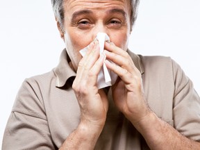 A man with a cold blows his nose. (Fotolia image)