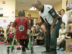 RedBlack's Quarterback Henry Burris got a chance to hang out with the kids from the Ottawa Children's Treatment Centre on Tuesday Sept 23,  2014. Burris is the new celebrity ambassador to the treatment centre. Each year more than 4,000 children and youth with physical and/or developmental disabilities use the service of the centre. Here a young student meets a smiling Burris.
Tony Caldwell/Ottawa Sun/QMI Agency