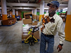 Emmanuel Kimuli carts a load of frozen goods to the freezer at the Daily Bread Food Bank in Toronto on Monday April 21, 2014. Kimuli, volunteers at the food bank to give back to the service that has helped him since coming to Canada in 2002 as a refugee. (Dave Abel/Toronto Sun/QMI Agency)