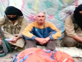 A man who identified himself as Herve Gourdel (C) sits in between two masked gunmen in this still image taken from video which was published on the Internet on September 22, 2014. REUTERS/The Caliphate Soldiers via Reuters TV