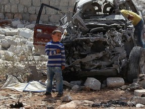 Boys inspect a vehicle which was damaged in what activists say was one of Tuesday's U.S. air strikes in Kfredrian, Idlib province September 24, 2014. The United States and its Arab allies bombed Syria for the first time on Tuesday, killing scores of Islamic State fighters and members of a separate al Qaeda-linked group, opening a new front against militants by joining Syria's three-year-old civil war.  REUTERS/Ammar Abdullah