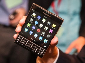 BlackBerry Chief Executive John Chen holds up the unreleased Blackberry Passport device during the company's annual general meeting for shareholders in Waterloo June 19, 2014. BlackBerry Ltd posted a narrower-than-expected loss as the troubled smartphone maker's turnaround efforts started to pay off, raising hopes Chen can deliver on a pledge to return the company to steady profits. REUTERS/Mark Blinch