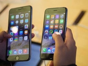 A customer holds an iPhone 6 (R) and iPhone 6 Plus after the phones went on sale at the Fifth Avenue Apple store in Manhattan, New York Sept. 19, 2014. REUTERS/Adrees Latif