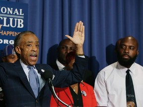 (L-R) U.S. civil rights leader Rev. Al Sharpton raises his hands in a "Don't Shoot" gesture next to the parents of Michael Brown, Lesley McSpadden (obscured) and Michael Brown, Sr. at a news conference at the National Press Club in Washington September 25, 2014. Five people were arrested and two police officers injured in renewed violence overnight on the streets of Ferguson, Missouri, sparked by a fire that destroyed a shrine to Michael Brown, a teenager killed by a police officer last month. REUTERS/Gary Cameron