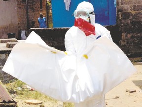 A Liberian Red Cross health worker, wearing a protective suit, carries the body of an 18-old-month baby, victim of the Ebola virus earlier this month in a district of Monrovia, the Liberian capital. (Zoom Dosso/AFP Photo)