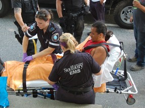 Paramedics treat a young man who was attacked by three suspects armed with baseball bats on Evergreen Street, behind the old Sudbury Star offices, on July 17, 2013.