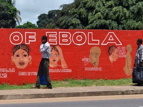 Pedestrians walk past a mural showing the symptoms of the Ebola virus in Monrovia, Liberia, September 26, 2014. REUTERS/James Giahyue