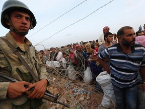 A Turkish soldier stands guard as Syrian Kurdish refugees wait behind the border fences to cross into Turkey near the southeastern town of Suruc in Sanliurfa province on September 27, 2014. (REUTERS/Murad Sezer)