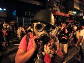 A protester puts on a gas mask to prepare for a possible tear gas attack as hundreds of protesters block a main road at Hong Kong's shopping Mongkok district September 29, 2014. (REUTERS/Liau Chung-ren)