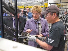 Premier Kathleen Wynne talks with an employee as she tours Brose Canada in London, Ont., in this February 27, 2014 file photo. Wynne was on hand to announce a $1 million grant to the auto parts maker through the Southwestern Ontario Development Fund. (CRAIG GLOVER/QMI Agency)