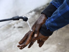 A visitor's hands are decontaminated by a health worker at Island Hospital as he arrives to deliver food to relatives. (AFP PHOTO / PASCAL GUYOT)