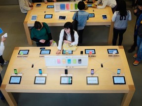 Customers look at Apple iPhone 5c and 5s at an Apple store in Beijing's Sanlitun area, Sept. 30, 2014. REUTERS/JASON LEE