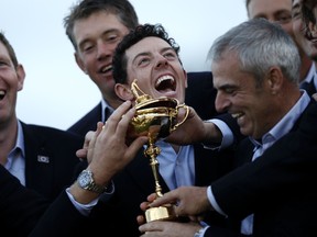Rory McIlroy of Northern Ireland (C) and Captain of Team Europe Paul McGinley (C) of Ireland pose with the trophy after retaining the Ryder Cup on the final day of the Ryder Cup golf tournament at the Gleneagles Hotel in Gleneagles, Scotland, on September 28, 2014. (AFP)