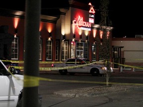 An RCMP cruiser idles while police tape marks the perimeter around a parking lot in front of The Canadian Brewhouse on 104A Avenue in Grande Prairie the morning of Oct. 1, 2014. (TOM BATEMAN/DAILY HERALD-TRIBUNE/QMI AGENCY)