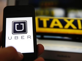 File illustration picture showing the logo of car-sharing service app Uber on a smartphone next to the picture of an official German taxi sign in Frankfurt. REUTERS/Kai Pfaffenbach/Files