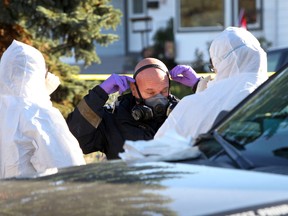 A fire investigator pulls on a mask as he and police prepare to go in to a house involved in a fatal fire at 173 Street and 77 Avenue in Edmonton, Alberta, on Oct. 1, 2014. A woman was found deceased in the home and police are calling the death suspicious. (Perry Mah/Edmonton Sun/QMI Agency)