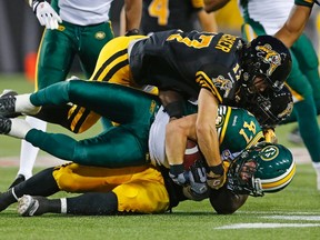 Edmonton Eskimos JC Sherritt (C) is tackled after intercepting the ball by Hamilton Tiger-Cats Luke Tasker during the first half of their CFL football in Hamilton, September 20, 2014.    REUTERS/Mark Blinch (CANADA - Tags: SPORT FOOTBALL)