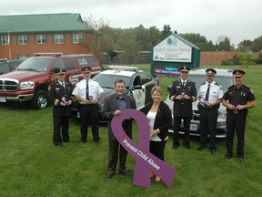 Family & Children's Services of St. Thomas and Elgin executive director Rod Potgieter and board of directors president Jennifer Paul-O'Donnell hold a purple ribbon in front of the F&CS building on Sunset Dr. The organization is distributing purple ribbons and adding them to police and fire vehicles as part of National Child Abuse and Neglect Prevention Month. Standing in back are St. Thomas Deputy Fire Chief Ray Ormerod, left, Aylmer Police Chief Andre Reymer, St. Thomas Fire Chief Rob Broadbent, Elgin OPP Insp. Brad Fishleigh and St. Thomas Police Chief Darryl Pinnell. 

Ben Forrest/Times-Journal