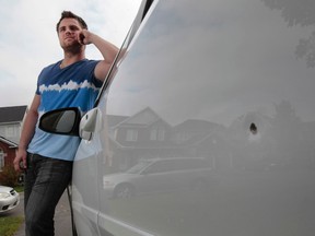 Justin Dionne stands beside his family car which was hit by a bullet in Ottawa Wednesday Oct 1,  2014. Justin Dionne's car was hot with some kind of bullet Sunday night. The family thinks it is was 22 caliber.   Tony Caldwell/Ottawa Sun/QMI Agency